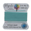 Spool of turquoise thread with Magnolia Bead Company label on a wooden surface