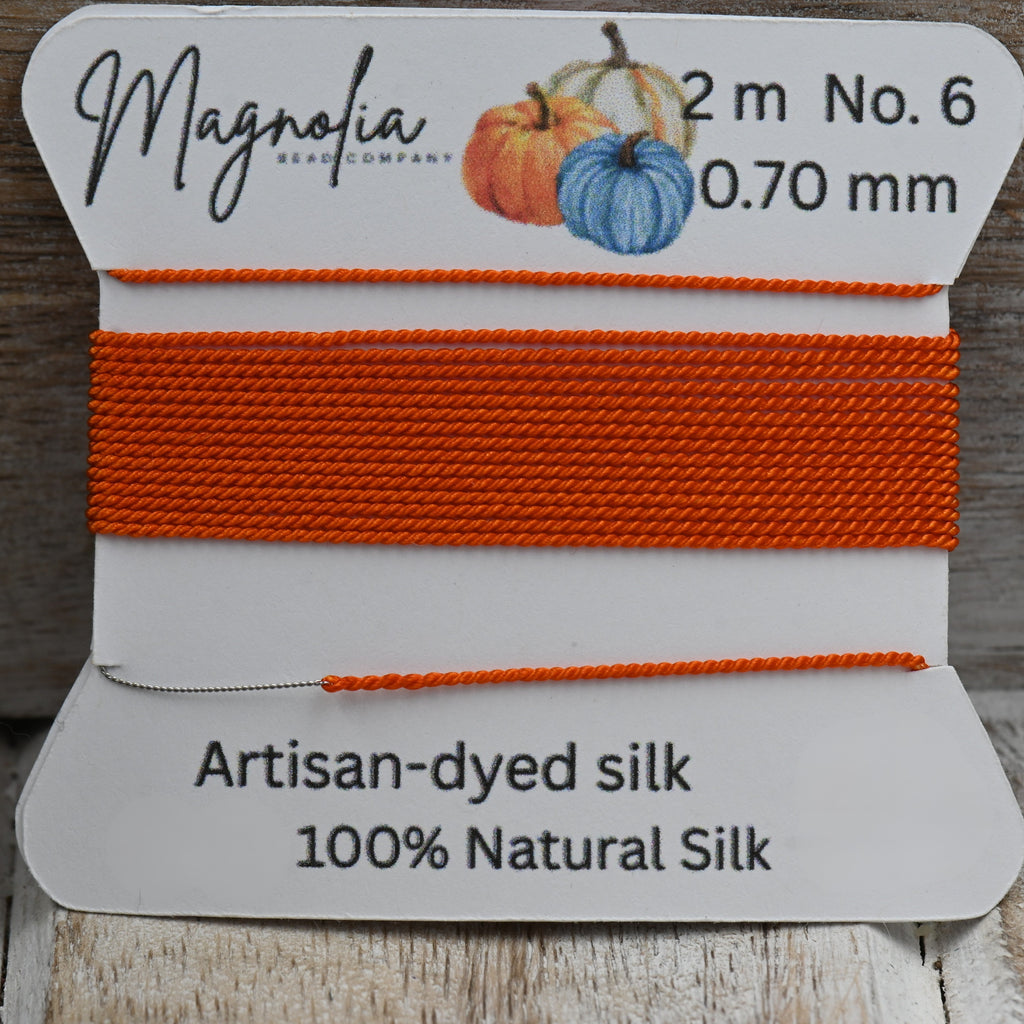 Orange silk thread on a Magnolia label with wooden background