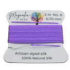Spool of purple thread with a label on a dark textured background