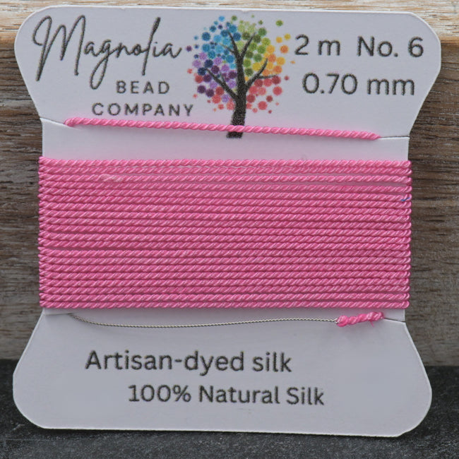 Pink thread on a card with Magnolia Bead Company branding against a wooden background Hover Image