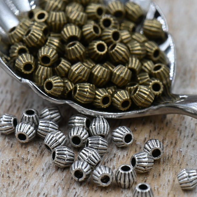 Bronze or Antique Silver, 4mm corrugated bicone. Sold per pkg of 100 Hover Image