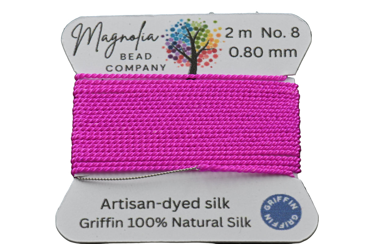 Pink thread spool with Magnolia Bead Company label on a dark background