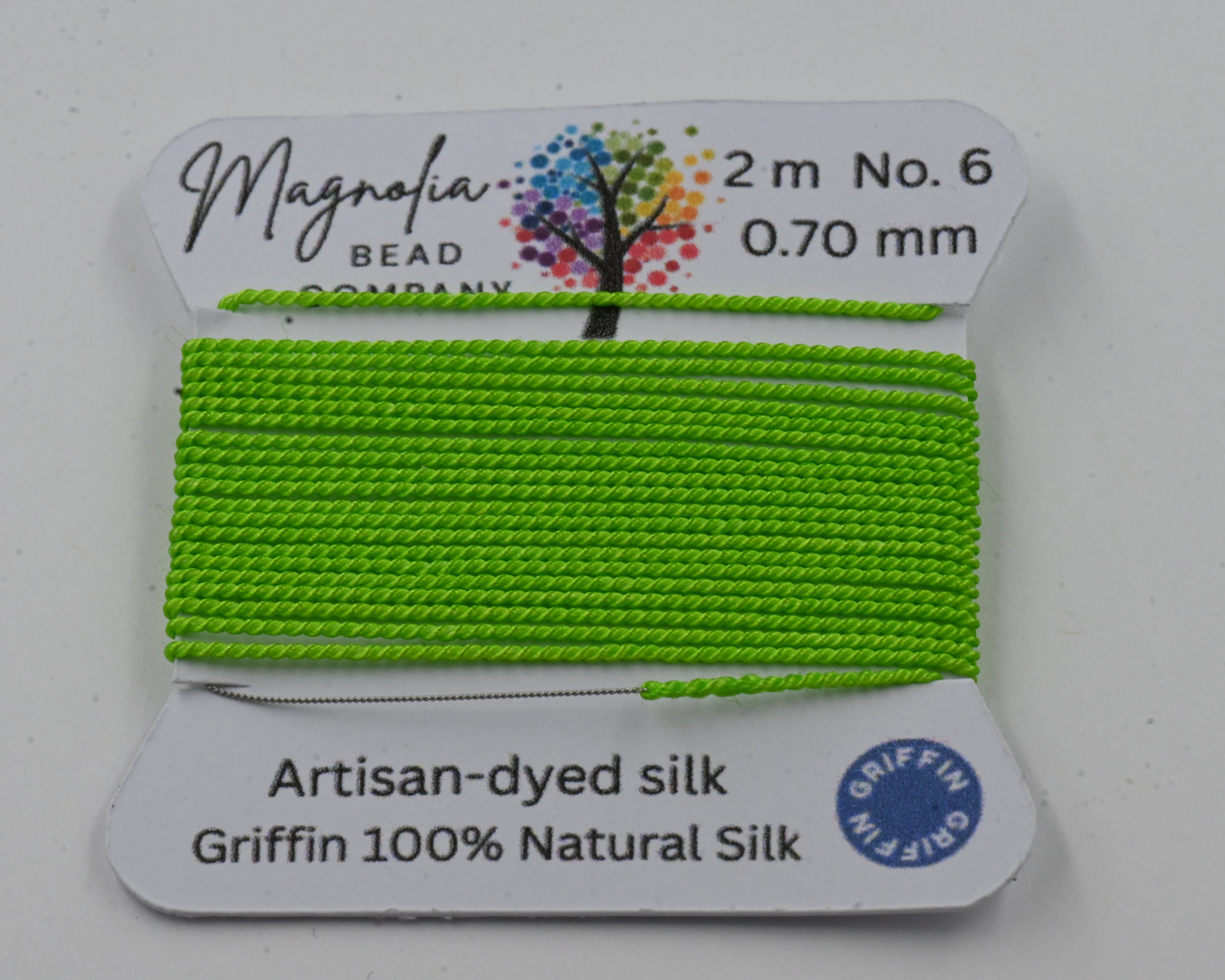 Green silk thread on a card with Magnolia Bead Company branding