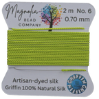 Lime green thread on a card with 'Magnolia Bead Company' branding against a wooden background