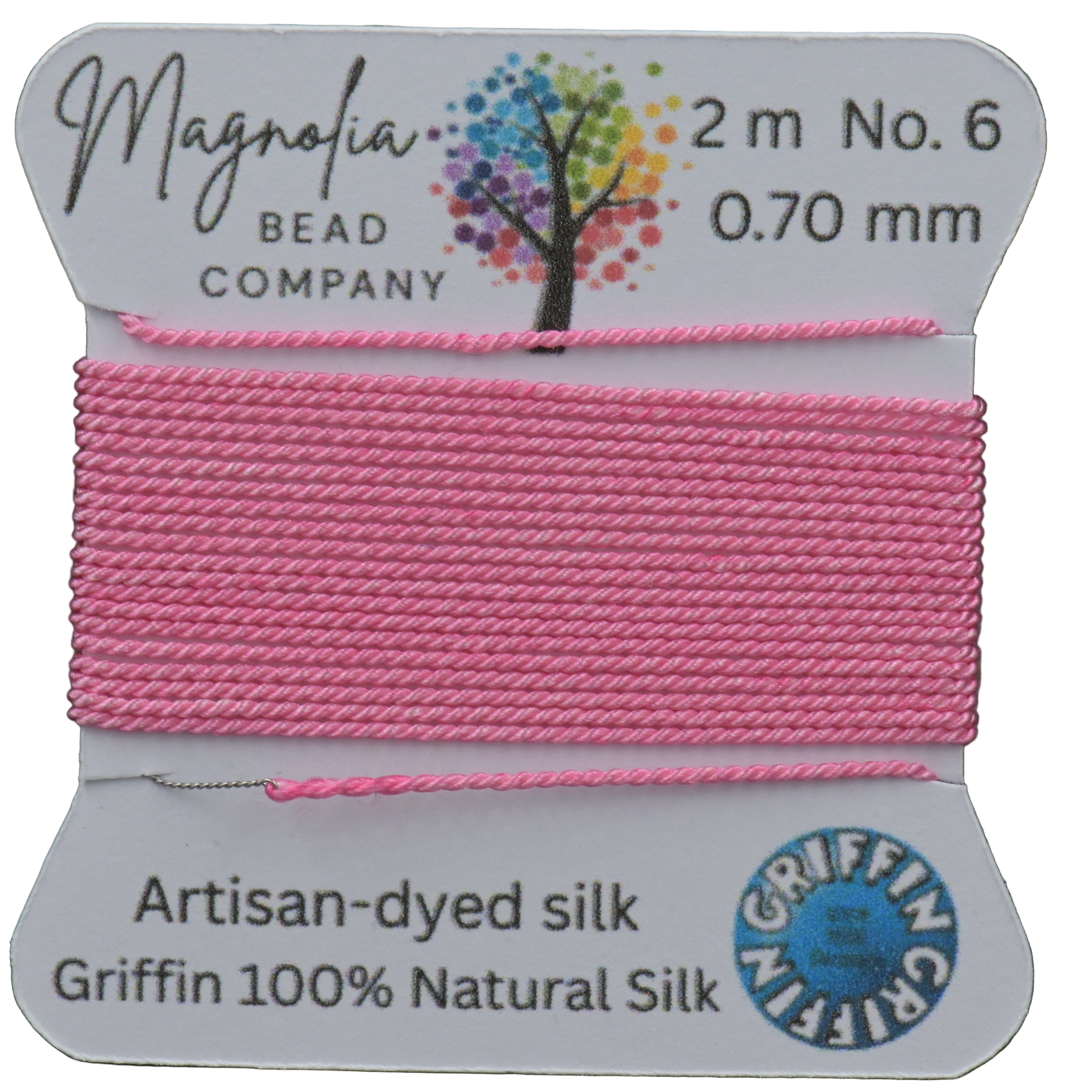 Pink thread spool with 'Magnolia Bead Company' label on a wooden surface