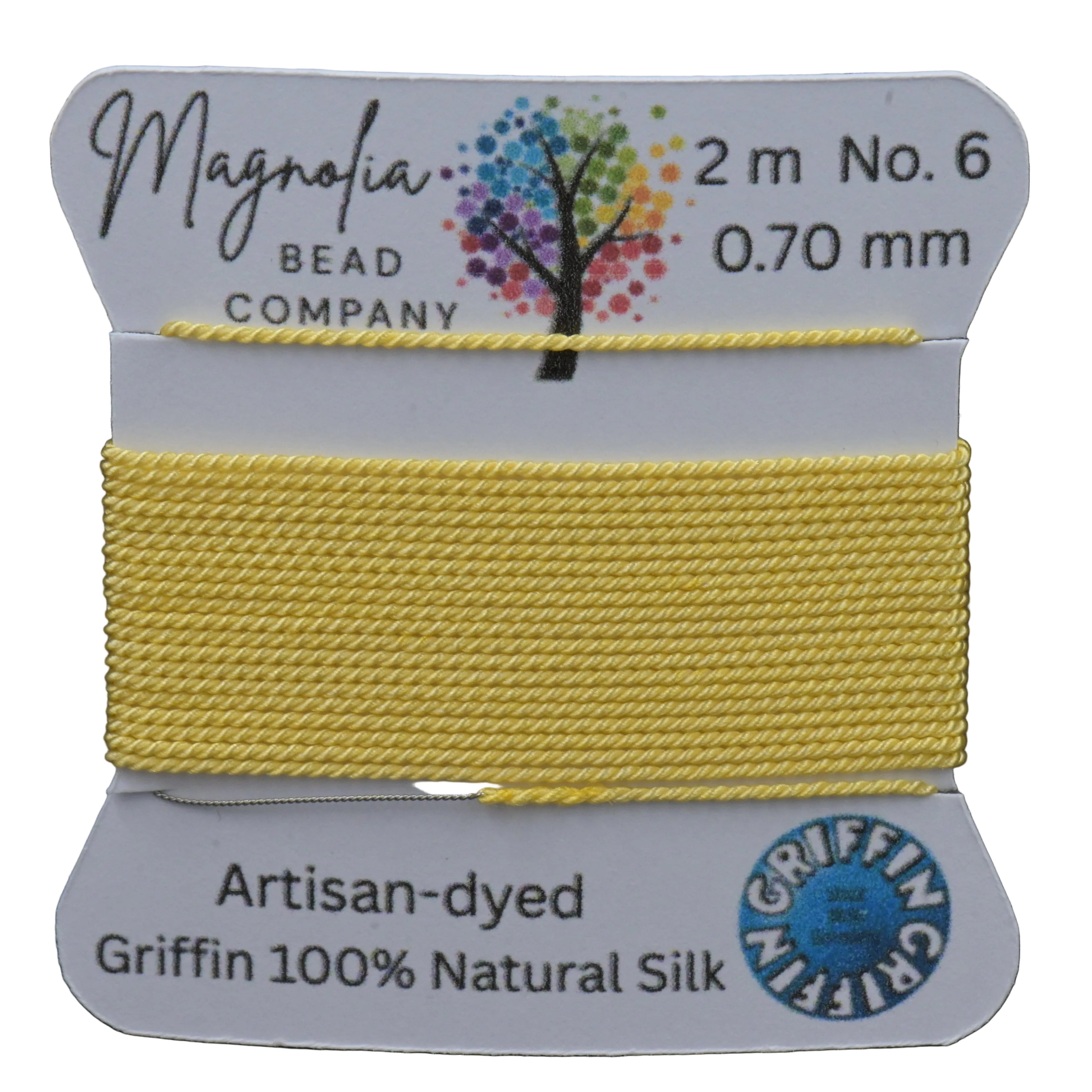 Yellow thread on a card with 'Magnolia Bead Company' branding against a wooden background