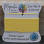 Yellow thread on a card with 'Magnolia Bead Company' branding against a wooden background