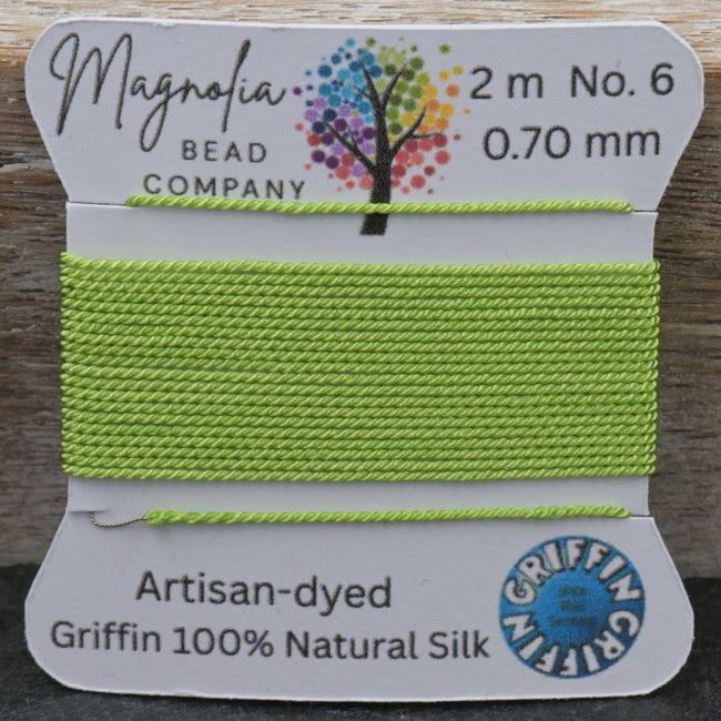 Green thread on a Griffin card with Magnolia Bead Company branding on a wooden surface. Hover Image