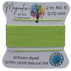 Spool of green thread with Magnolia Bead Company label on a wooden background