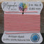 Pink thread on a spool with Magnolia Bead Company label on a wooden surface
