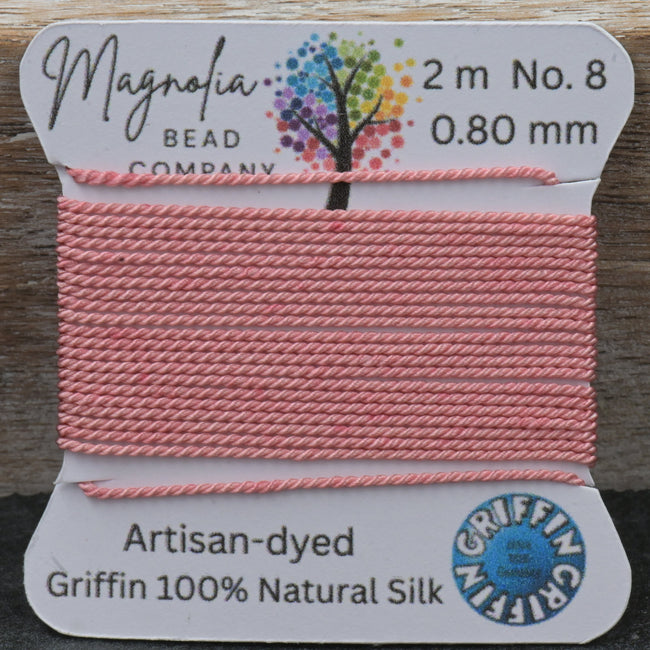 Pink thread on a spool with Magnolia Bead Company label on a wooden surface Hover Image