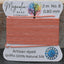 Spool of orange thread with a label from Magnolia Bead Company on a wooden surface.