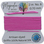 Pink thread on a card with Magnolia Bead Company branding against a wooden background