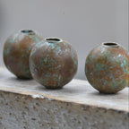 Four metallic beads on a concrete surface with a blurred background