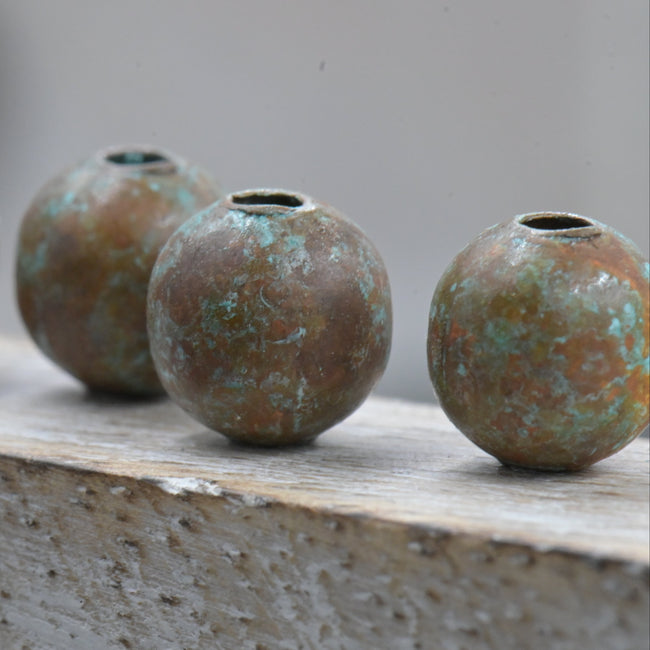 Four metallic beads on a concrete surface with a blurred background Hover Image