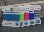Set of colorful thread spools with labels on a dark surface