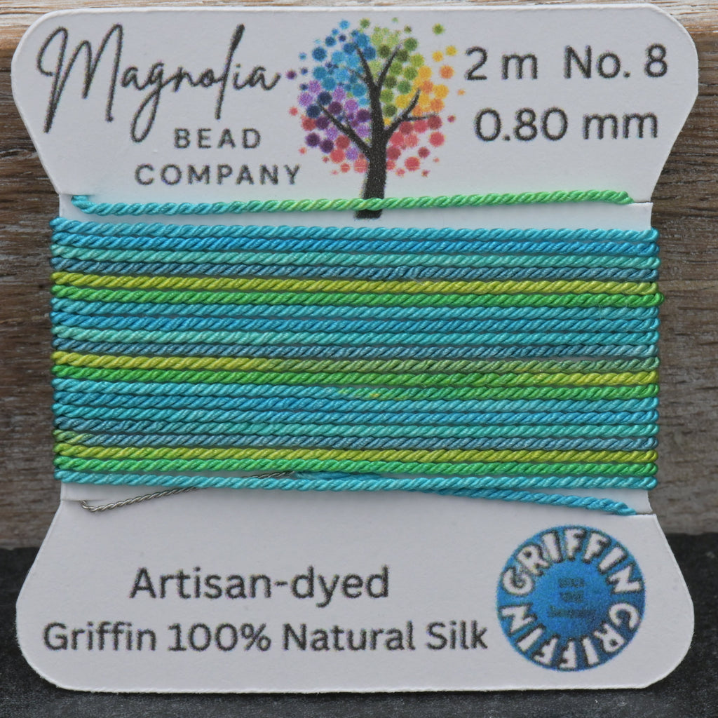 Spool of colorful thread with Magnolia Bead Company label on a wooden surface