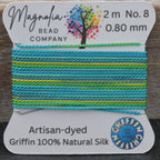 Spool of colorful thread with Magnolia Bead Company label on a wooden surface