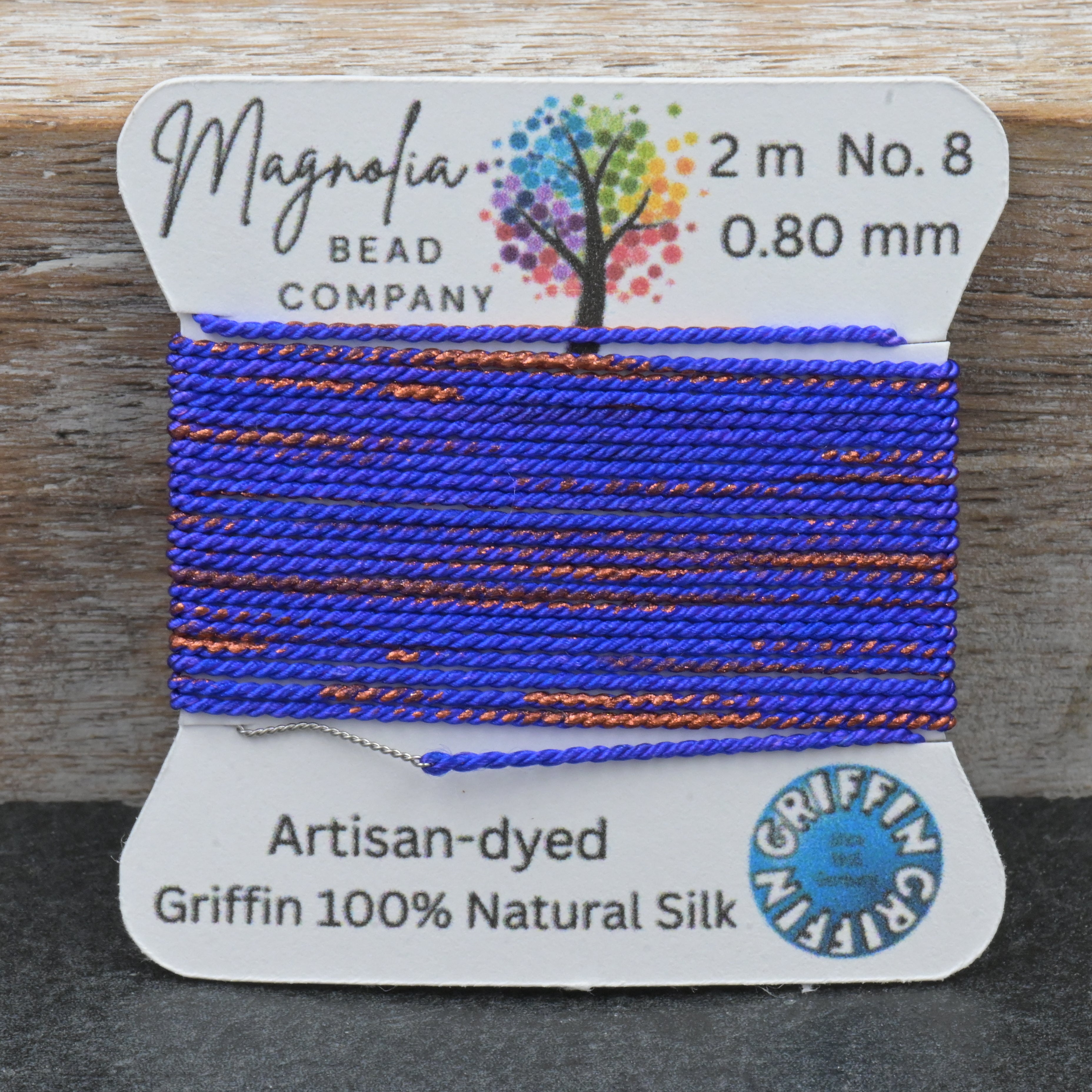 Bead thread on a card with 'Magnolia Bead Company' branding on a wooden surface.