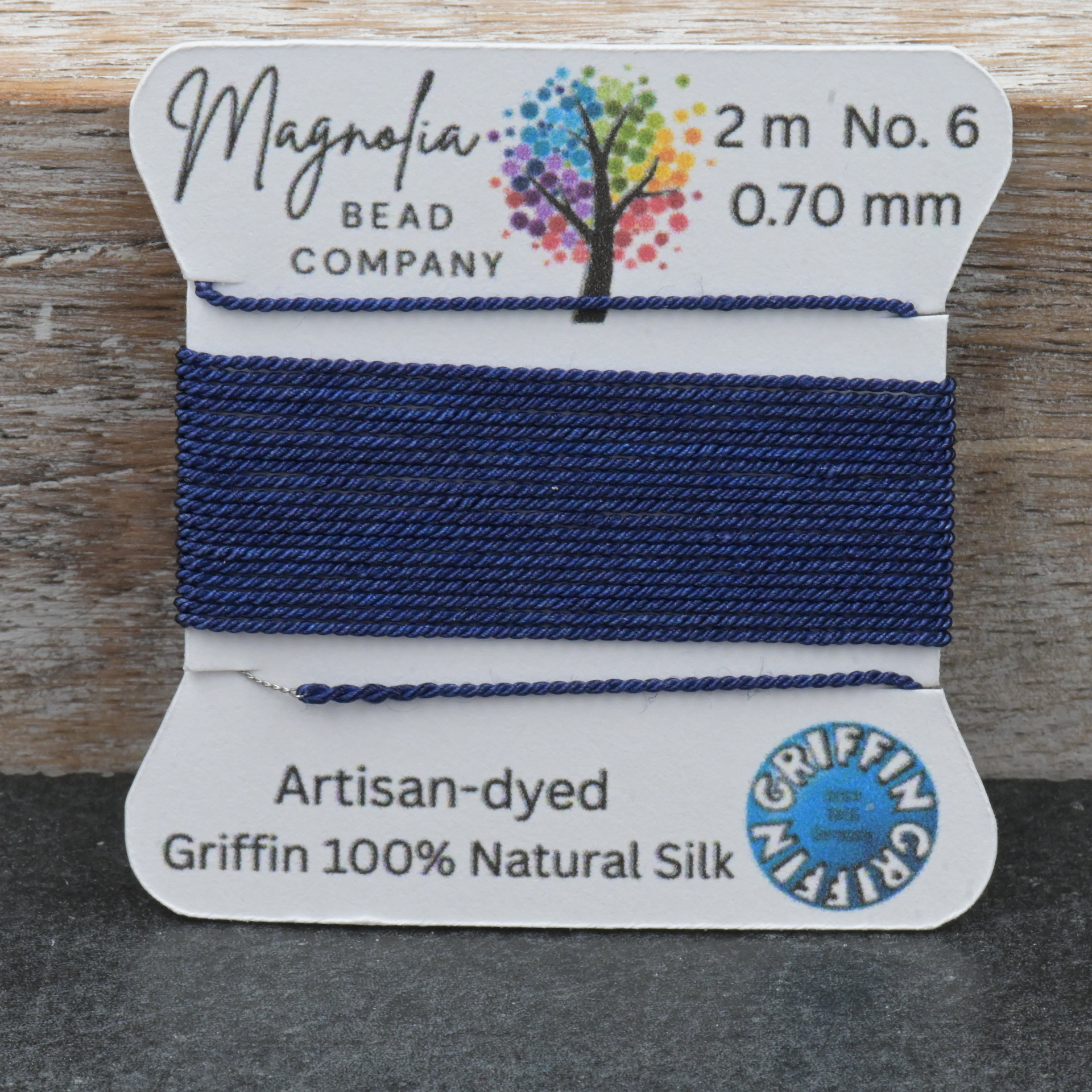 Bead thread on a card with 'Magnolia Bead Company' branding on a wooden surface.