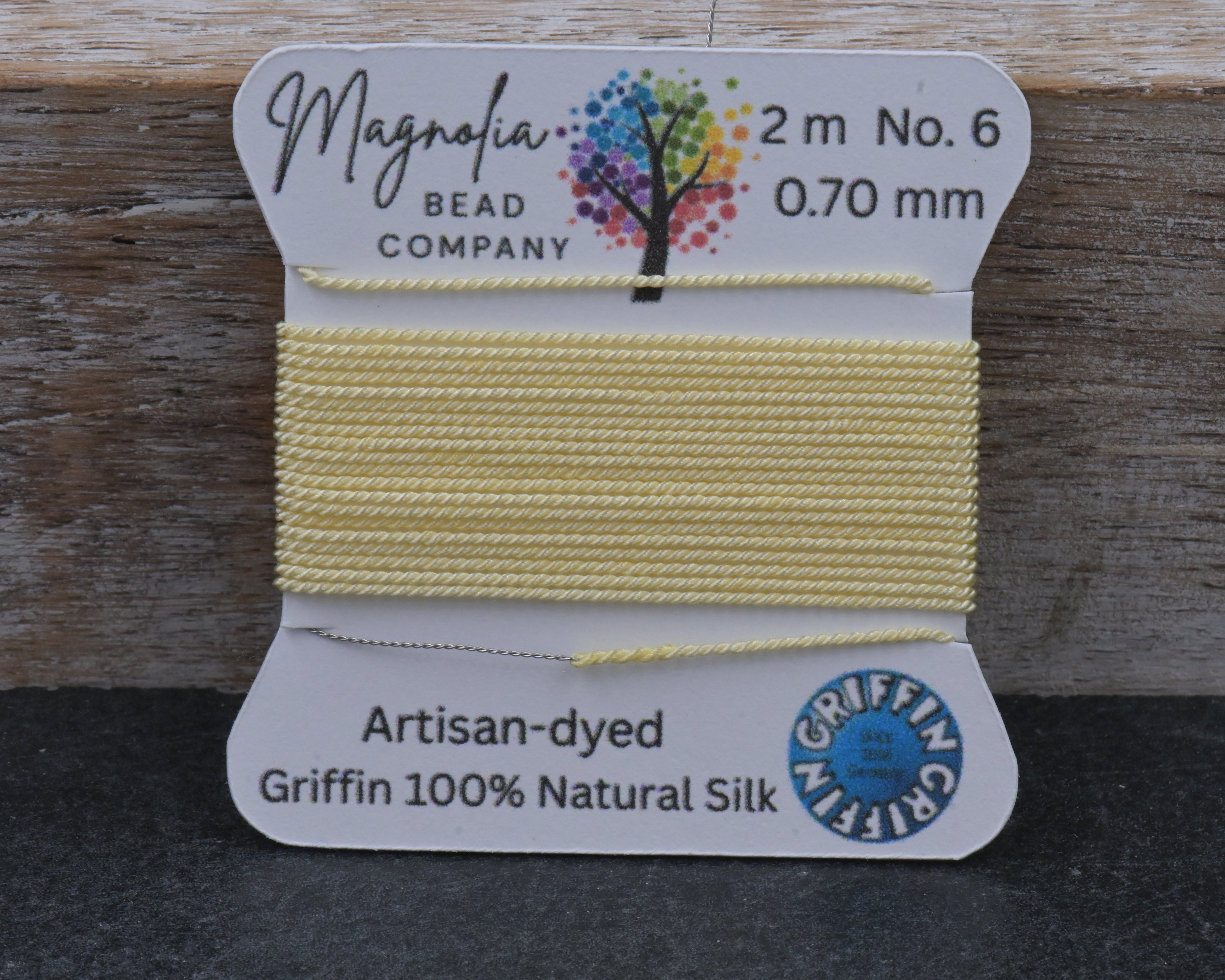 Spool of yellow thread on a branded card with 'Magnolia Bead Company' branding.