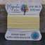 Yellow thread spool with Magnolia Bead Company packaging on a wooden surface