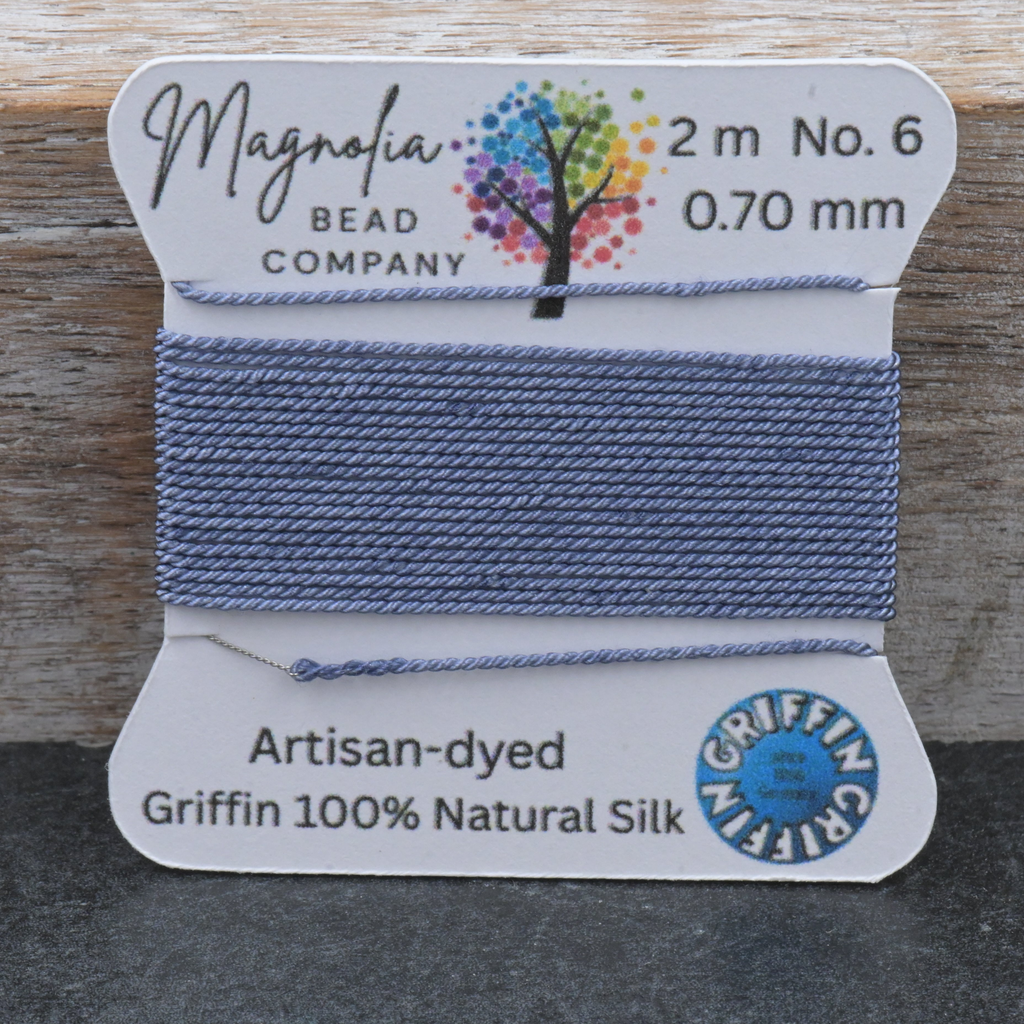 Bead thread on a card with 'Magnolia Bead Company' branding on a wooden surface.