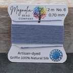 Bead thread on a card with 'Magnolia Bead Company' branding on a wooden surface.