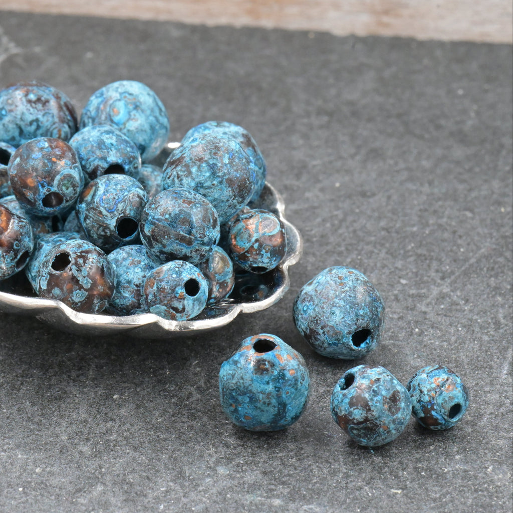 Blue beads in a silver spoon on a gray surface