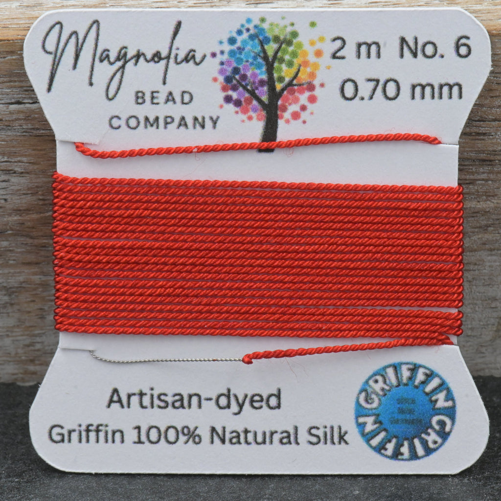 A spool of bright red silk thread from the Magnolia Bead Company, labeled as Griffin 100% Natural Silk, size No. 6, 0.