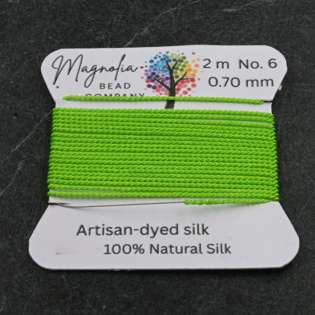 Green silk thread on a label with Magnolia Bead Company branding on a dark background