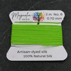 Green silk thread on a label with Magnolia Bead Company branding on a dark background